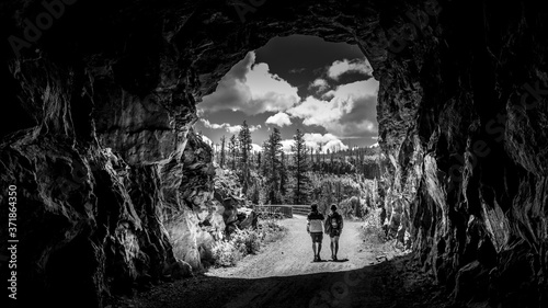 Black and White photo of a tunnel of the abandoned Kettle Valley Railway carved in the rocks of Myra Canyon near Kelowna, British Columbia, Canada 