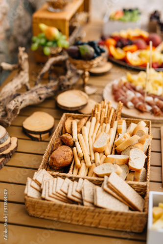 Wicker bread and cereal tray with sliced loaf, bread sticks and cookies on a wooden holiday table.