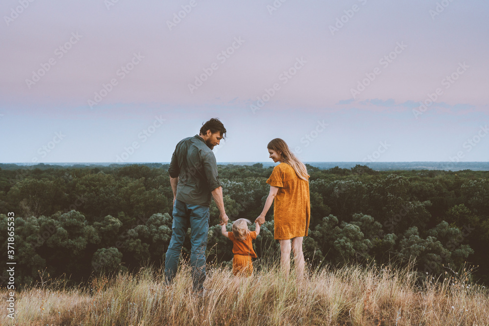 Family parents mother and father with baby holding hands walking outdoor together healthy lifestyle rural nature forest landscape