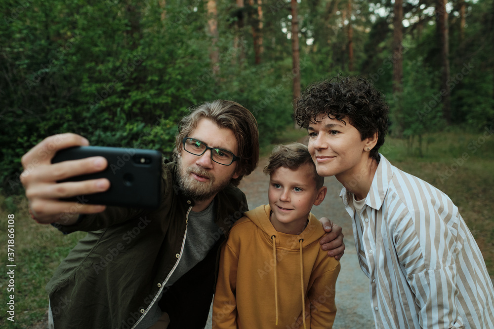 Contemporary family of happy parents and their son standing close to each other Contemporary family of happy parents and their son standing close to each other