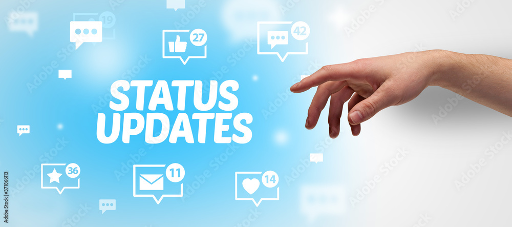 Close-Up of cropped hand pointing at STATUS UPDATES inscription, social networking concept Close-Up of cropped hand pointing at STATUS UPDATES inscription, social networking concept