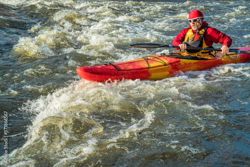 senior whitewater kayaker paddling upstream the river rapid - the Poudre River, Fort Collins, Colorado