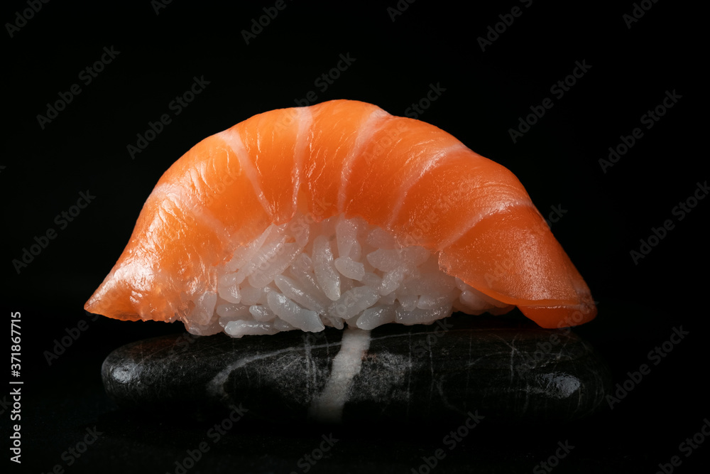 One sushi salmon on a rock in the dark One sushi salmon on a rock in the dark