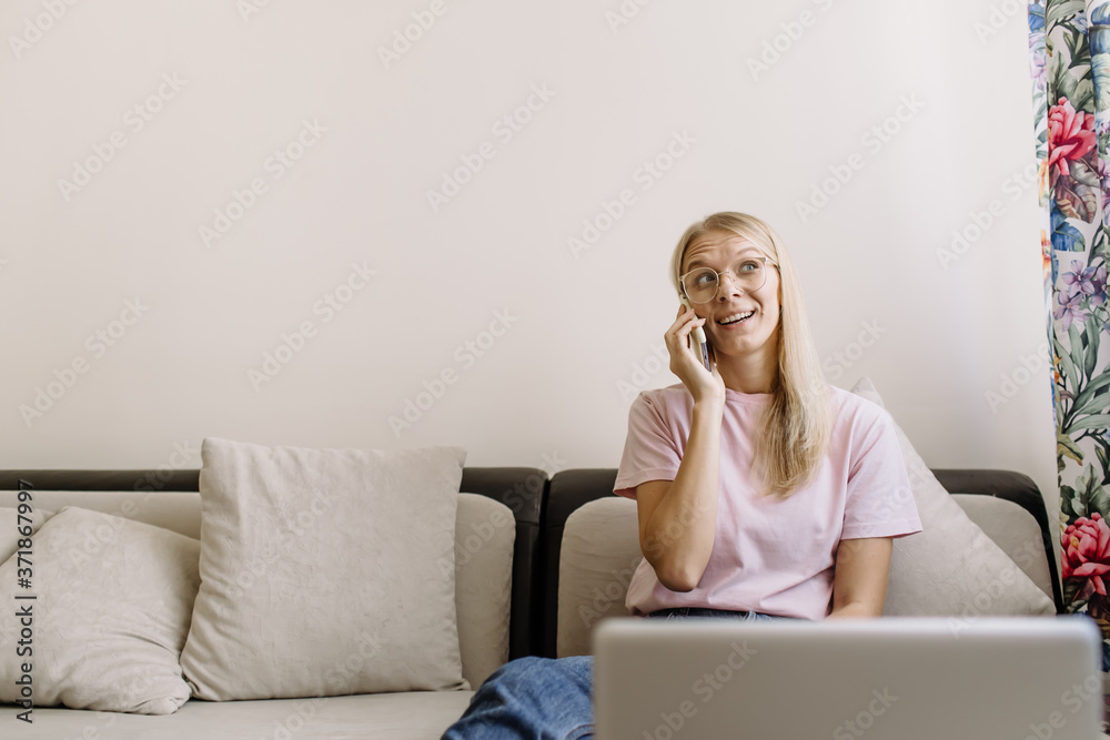 Smiling casual freelancer using smart phone and laptop while sitting on the sofa. Smiling casual freelancer using smart phone and laptop while sitting on the sofa.