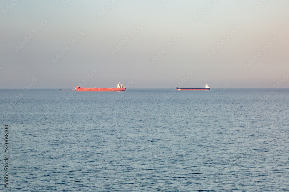 Calm sea, sky and two barges on the horizon. Horizontal orientation.