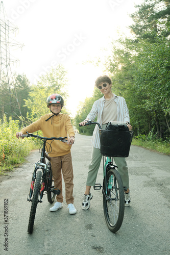 Happy young mother in casualwear and sunglasses and her youthful son in helmet