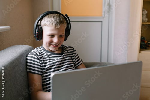 Obraz na plátně Boy with laptop doing homework with headphone.