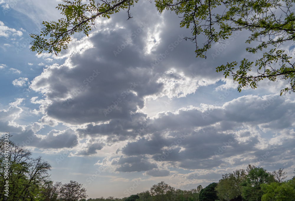 Summer sky with clouds and sun rays between them Summer sky with clouds and sun rays between them
