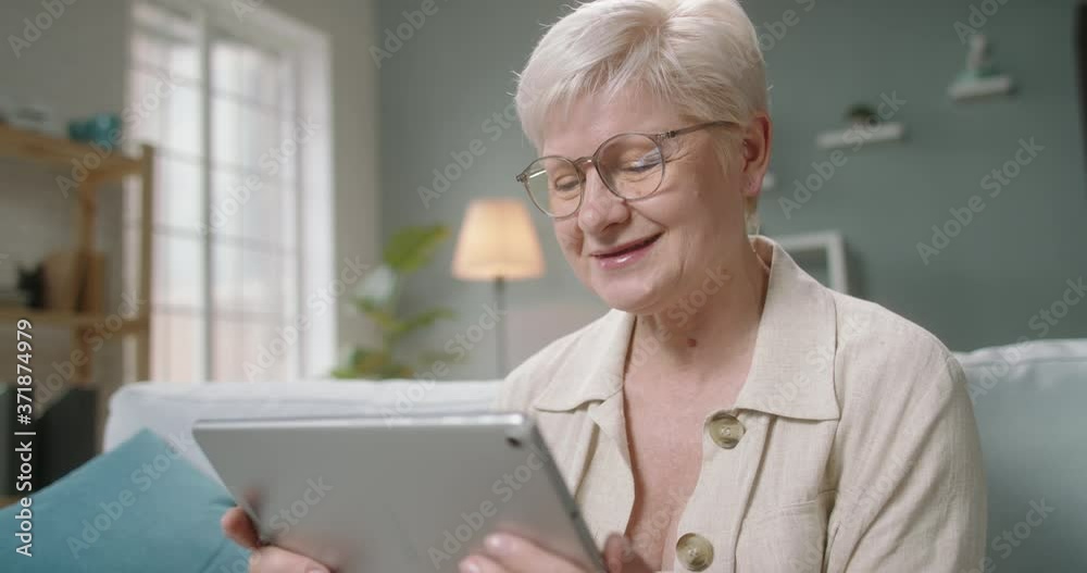 Senior caucasian lady having video chat with relatives or consulting with doctor during self-isolation, using tablet computer at home 4k footage Senior caucasian lady having video chat with relatives or consulting with doctor during self-isolation, using tablet computer at home 4k footage