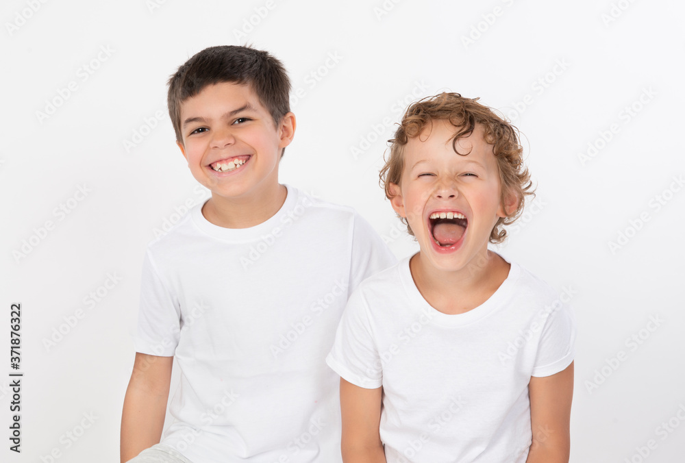 Happy laughing young brothers in white tee shirts sitting isolated on background Happy laughing young brothers in white tee shirts sitting isolated on background