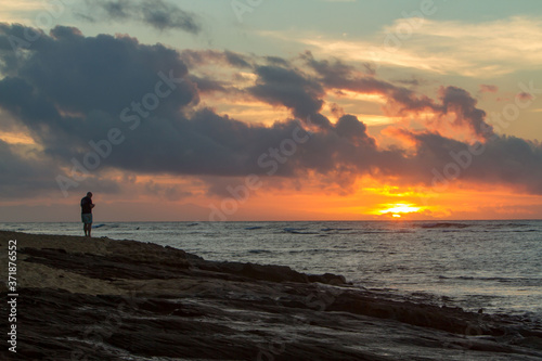 A lone man watching the sunset on the east shore of Oahu, Hawaii