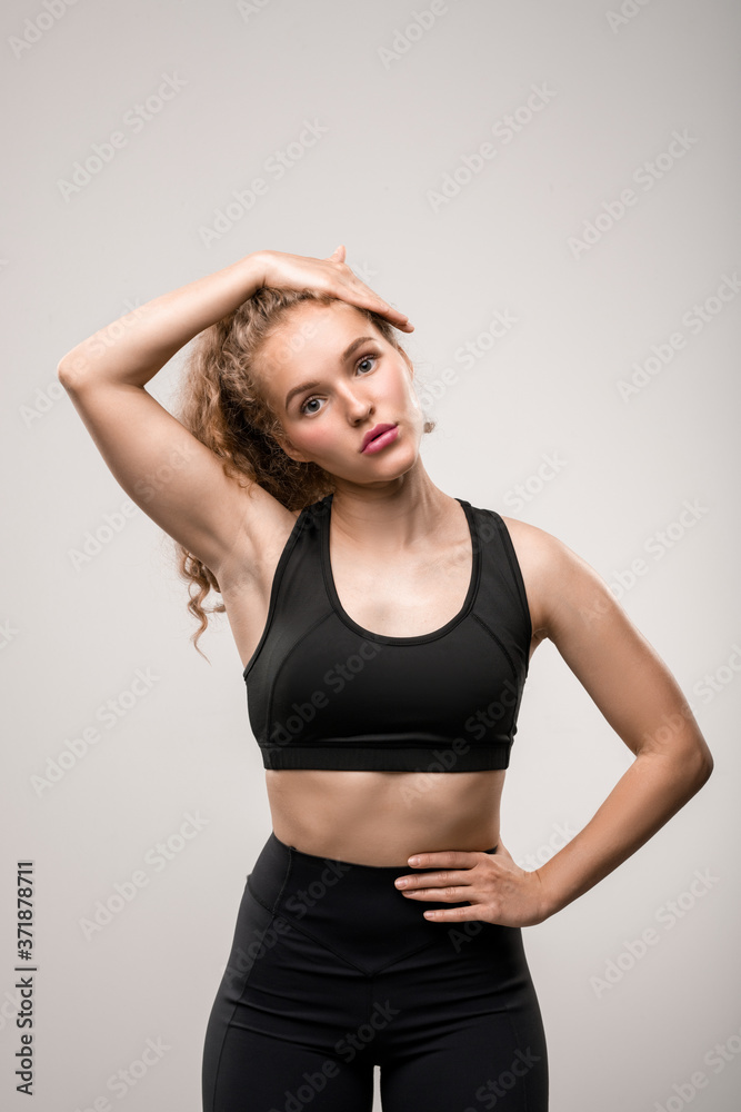 Fit young woman in black tracksuit touching her long blond curly hair Fit young woman in black tracksuit touching her long blond curly hair