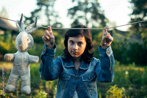 Teenage girl dries a toy hare on a clothesline.
