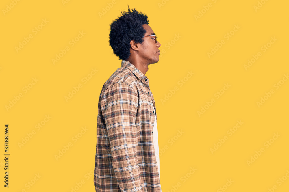 Handsome african american man with afro hair wearing casual clothes and glasses looking to side, relax profile pose with natural face and confident smile. Handsome african american man with afro hair wearing casual clothes and glasses looking to side, relax profile pose with natural face and confident smile.