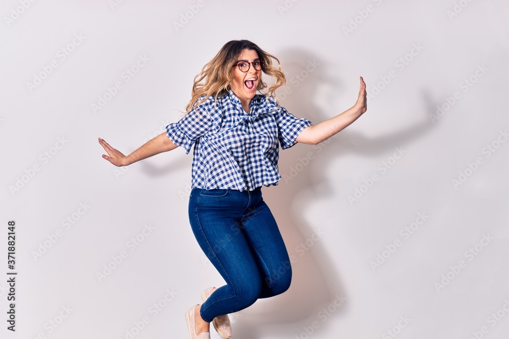 Young beautiful caucasian woman wearing casual clothes and glasses smiling happy. Jumping with smile on face over isolated white background Young beautiful caucasian woman wearing casual clothes and glasses smiling happy. Jumping with smile on face over isolated white background