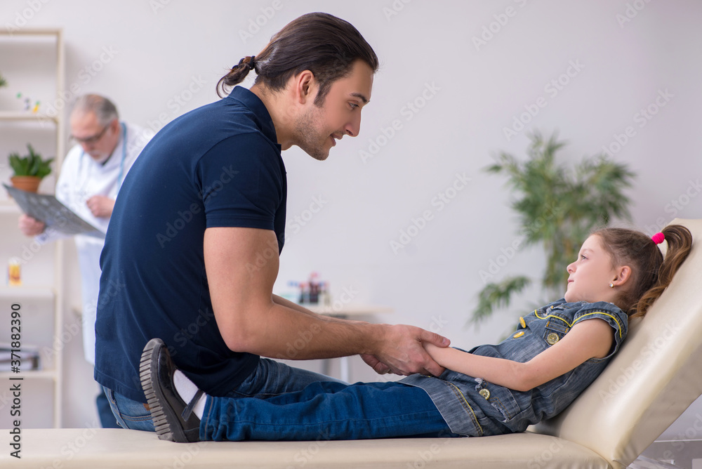 Young father and his daughter visiting old male doctor