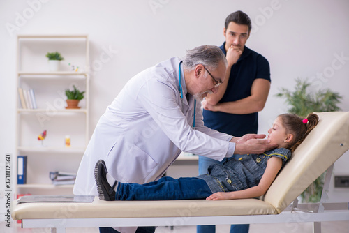 Young father and his daughter visiting old male doctor