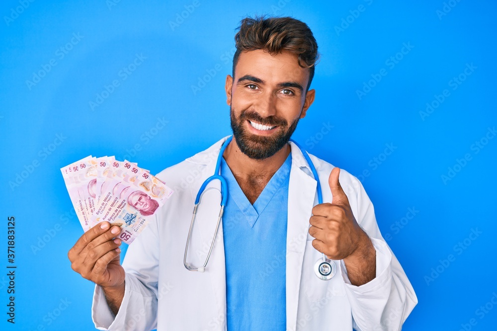 Young hispanic man wearing doctor uniform holding mexican pesos smiling happy and positive, thumb up doing excellent and approval sign Young hispanic man wearing doctor uniform holding mexican pesos smiling happy and positive, thumb up doing excellent and approval sign