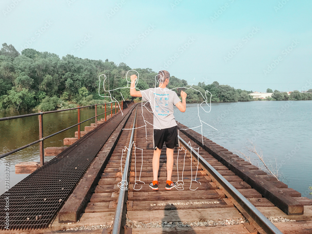 young man dancing on a railroad track over a river