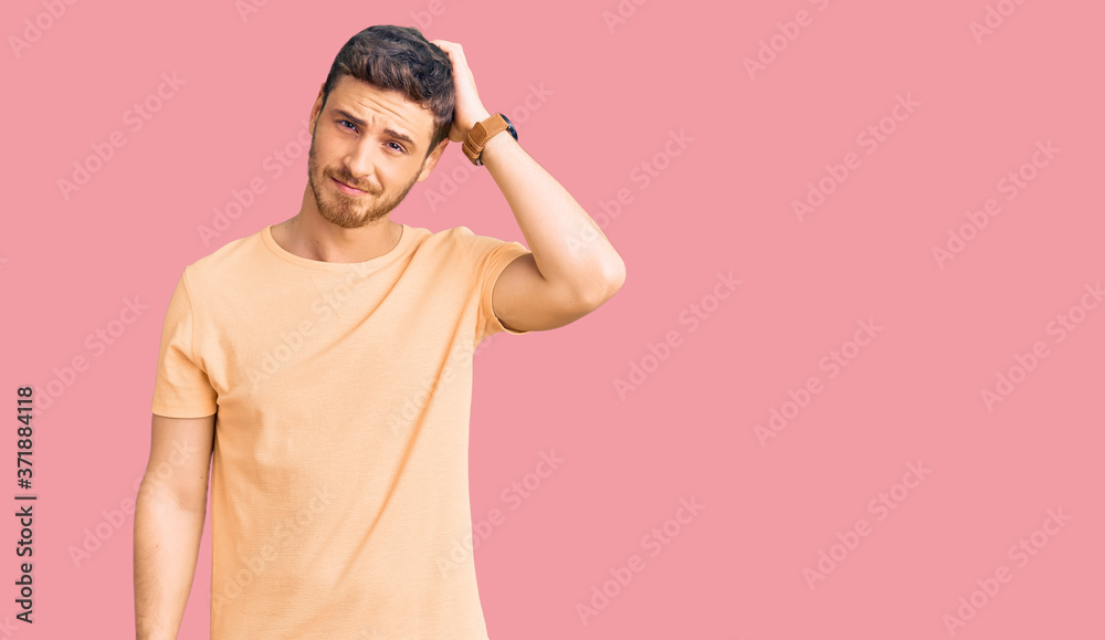 Handsome young man with bear wearing casual yellow tshirt confuse and wonder about question. uncertain with doubt, thinking with hand on head. pensive concept. Handsome young man with bear wearing casual yellow tshirt confuse and wonder about question. uncertain with doubt, thinking with hand on head. pensive concept.