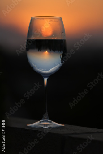 Reflection of the sun and sunset in a bright orange sky through a glass of wine. 