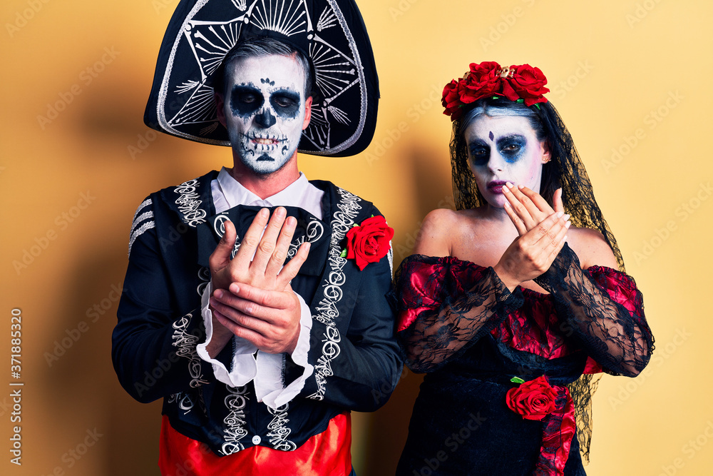 Young couple wearing mexican day of the dead costume over yellow suffering pain on hands and fingers, arthritis inflammation