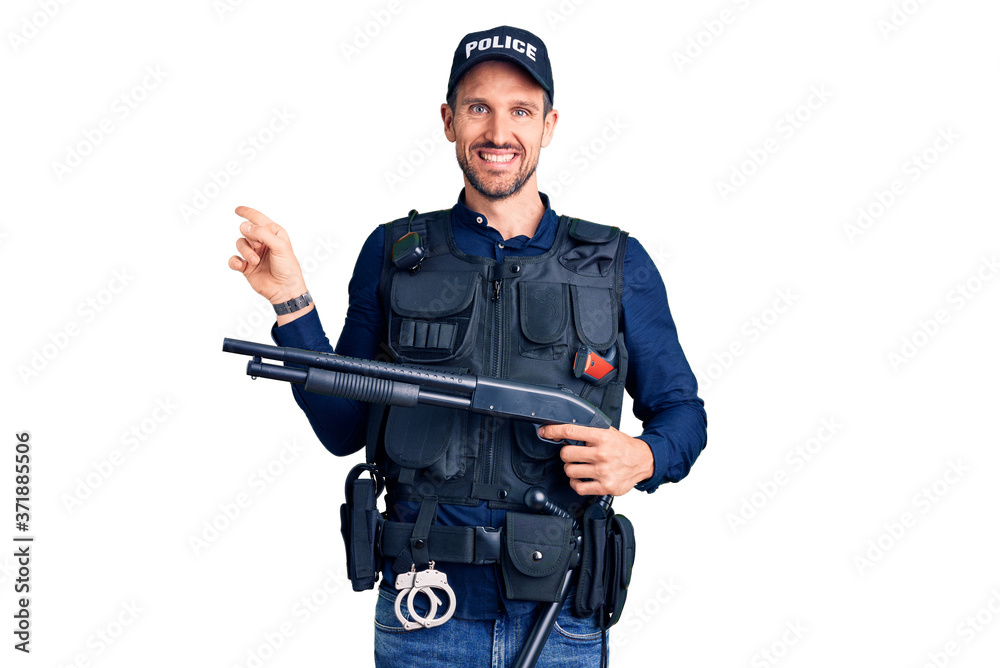 Young handsome man wearing police uniform holding shotgun smiling happy pointing with hand and finger to the side Young handsome man wearing police uniform holding shotgun smiling happy pointing with hand and finger to the side