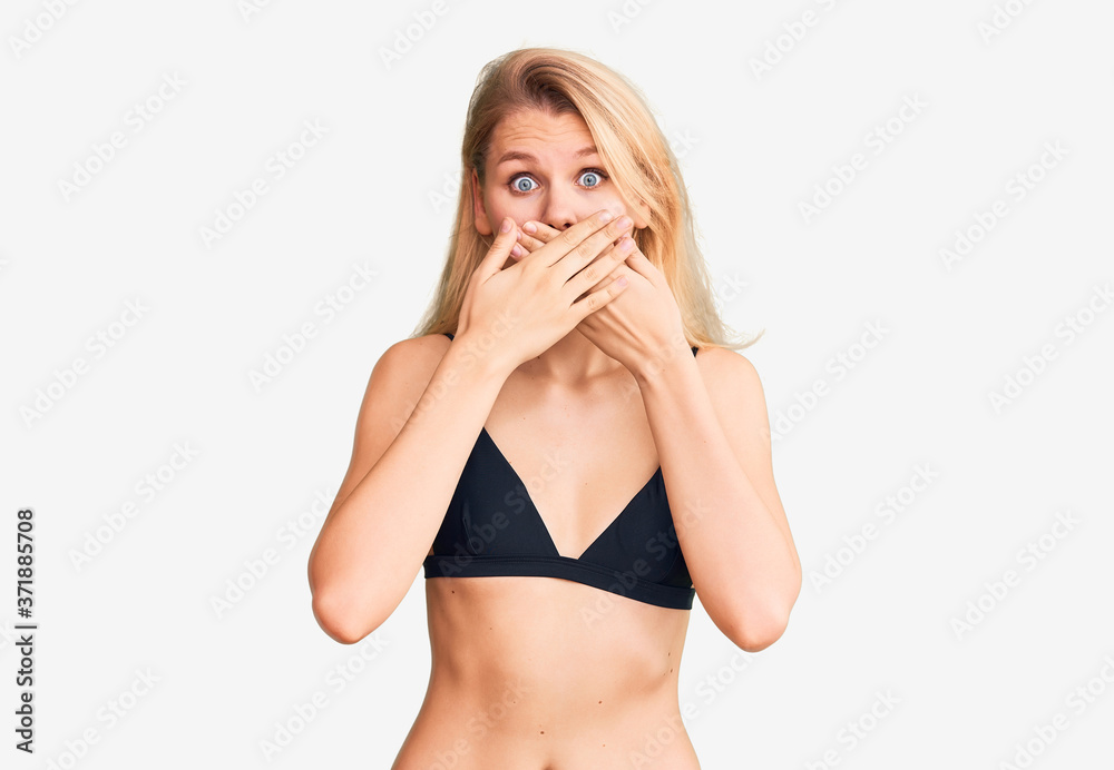 Young beautiful blonde woman wearing bikini shocked covering mouth with hands for mistake. secret concept. Young beautiful blonde woman wearing bikini shocked covering mouth with hands for mistake. secret concept.