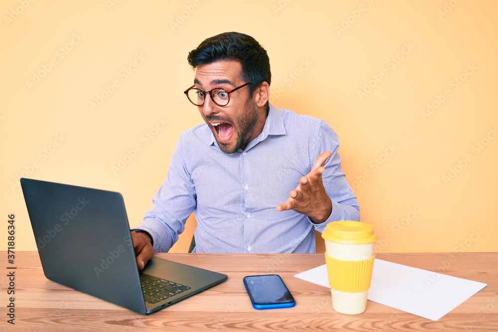 Young hispanic man working at the office drinking a cup of coffee celebrating victory with happy smile and winner expression with raised hands Young hispanic man working at the office drinking a cup of coffee celebrating victory with happy smile and winner expression with raised hands