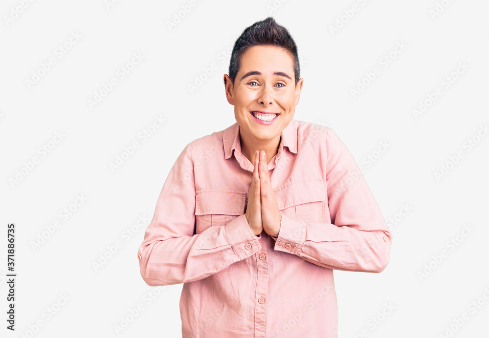 Young woman with short hair wearing casual clothes praying with hands together asking for forgiveness smiling confident. Young woman with short hair wearing casual clothes praying with hands together asking for forgiveness smiling confident.
