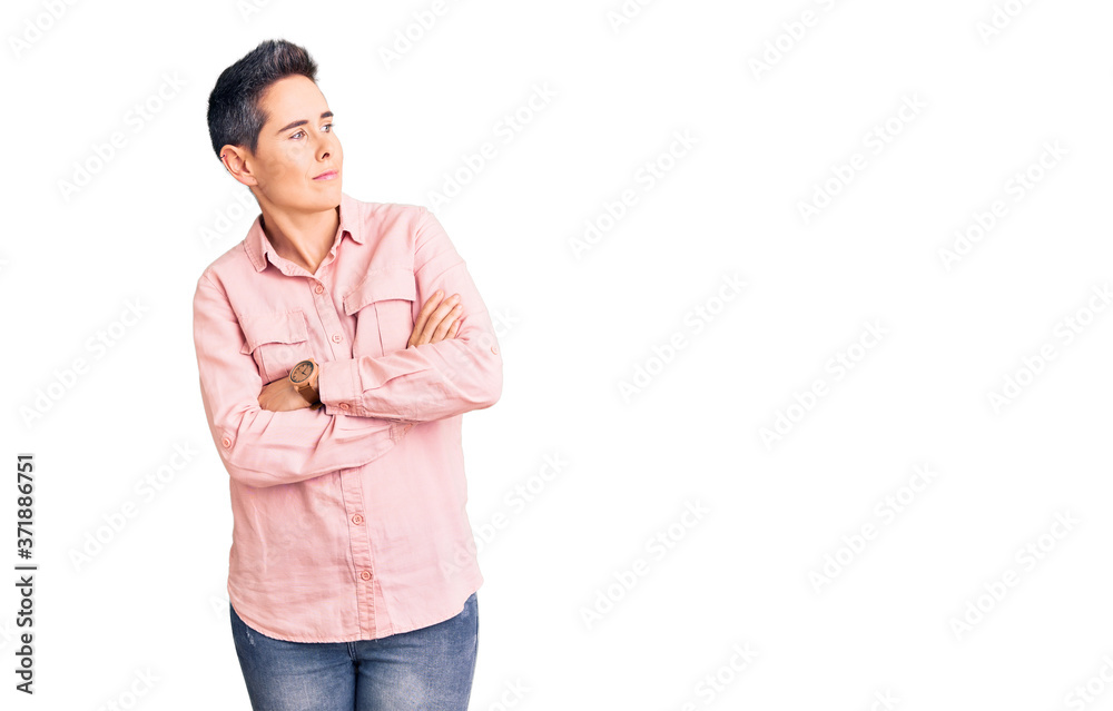 Young woman with short hair wearing casual clothes looking to the side with arms crossed convinced and confident Young woman with short hair wearing casual clothes looking to the side with arms crossed convinced and confident
