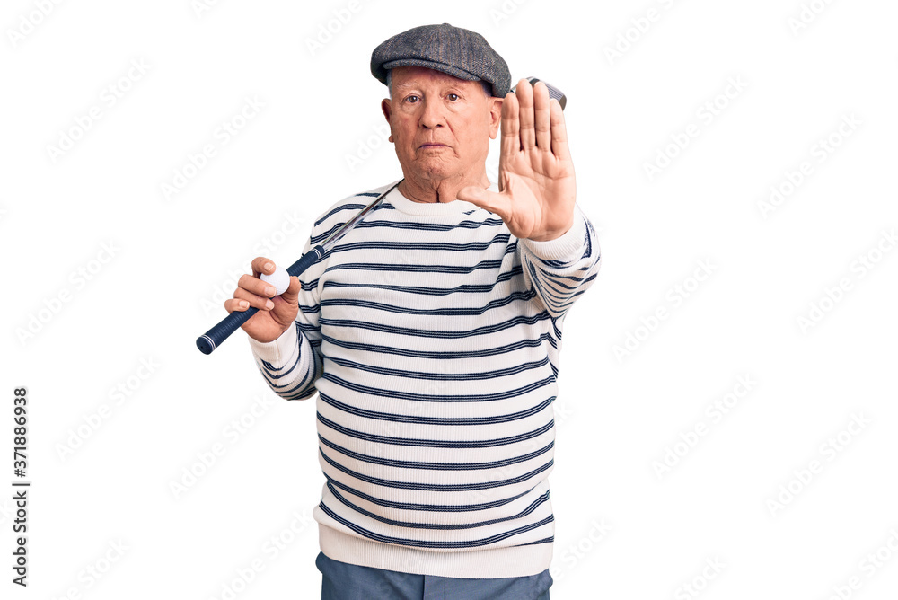 Senior handsome grey-haired man holding golf club and ball with open hand doing stop sign with serious and confident expression, defense gesture Senior handsome grey-haired man holding golf club and ball with open hand doing stop sign with serious and confident expression, defense gesture