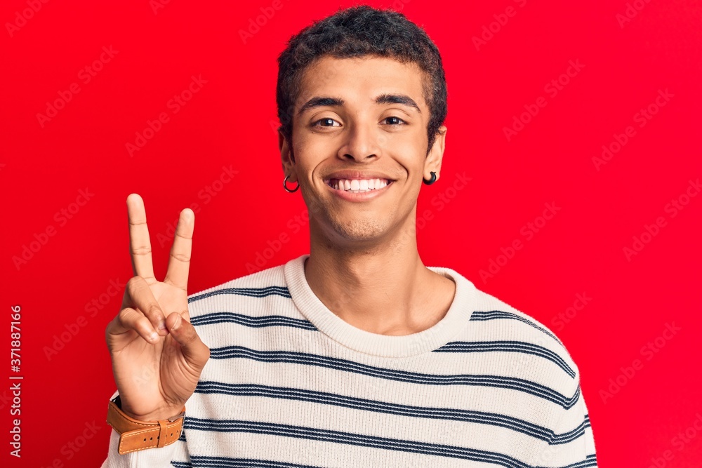 Young african amercian man wearing casual clothes smiling with happy face winking at the camera doing victory sign. number two. Young african amercian man wearing casual clothes smiling with happy face winking at the camera doing victory sign. number two.