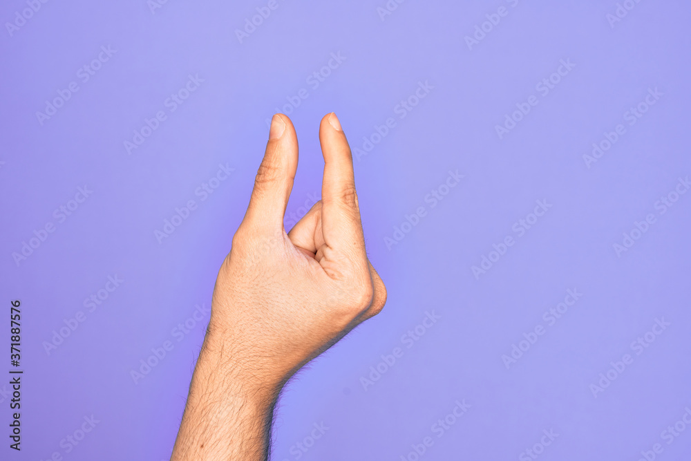Hand of caucasian young man showing fingers over isolated purple background picking and taking invisible thing, holding object with fingers showing space Hand of caucasian young man showing fingers over isolated purple background picking and taking invisible thing, holding object with fingers showing space