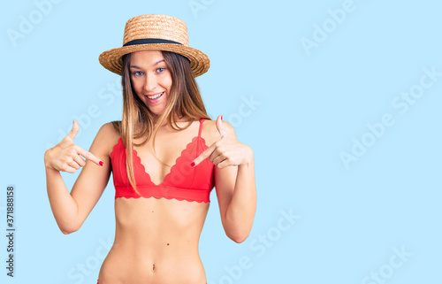 Beautiful brunette young woman wearing bikini looking confident with smile on face, pointing oneself with fingers proud and happy.