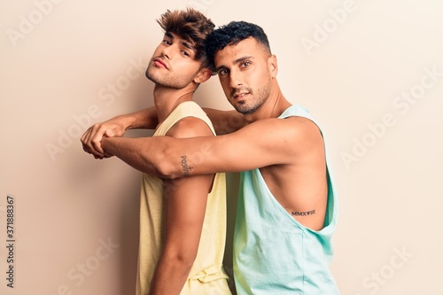 Young couple of men wearing summer clothes smiling happy. Standing with smile on face hugging over isolated white background