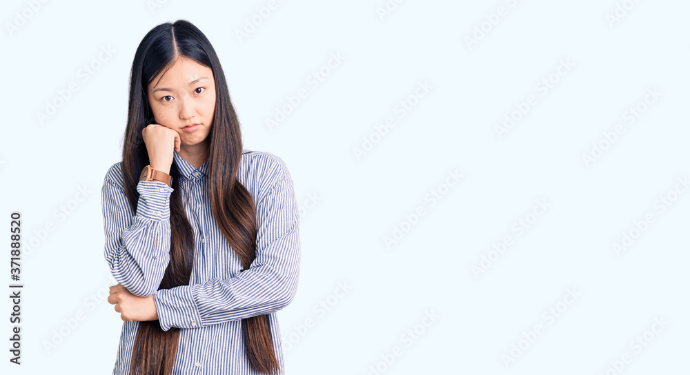 Young beautiful chinese woman wearing casual shirt thinking looking tired and bored with depression problems with crossed arms. Young beautiful chinese woman wearing casual shirt thinking looking tired and bored with depression problems with crossed arms.