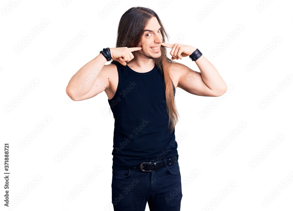 Young adult man with long hair wearing goth style with black clothes smiling cheerful showing and pointing with fingers teeth and mouth. dental health concept. Young adult man with long hair wearing goth style with black clothes smiling cheerful showing and pointing with fingers teeth and mouth. dental health concept.