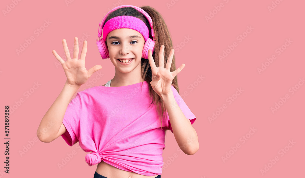 Cute hispanic child girl wearing gym clothes and using headphones showing and pointing up with fingers number nine while smiling confident and happy. Cute hispanic child girl wearing gym clothes and using headphones showing and pointing up with fingers number nine while smiling confident and happy.