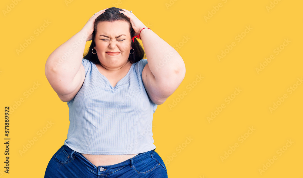 Young plus size woman wearing casual clothes suffering from headache desperate and stressed because pain and migraine. hands on head. Young plus size woman wearing casual clothes suffering from headache desperate and stressed because pain and migraine. hands on head.