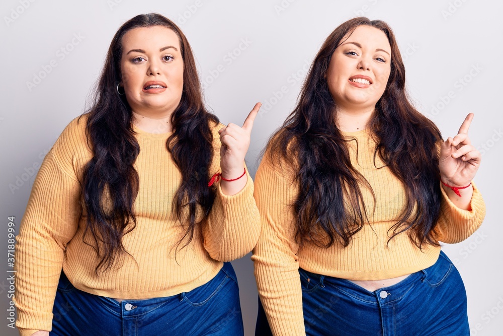 Young plus size twins wearing casual clothes pointing aside worried and nervous with both hands, concerned and surprised expression Young plus size twins wearing casual clothes pointing aside worried and nervous with both hands, concerned and surprised expression