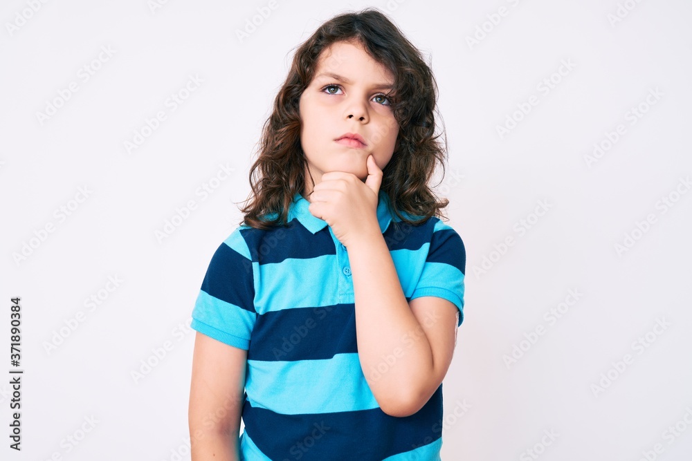 Cute hispanic child with long hair wearing casual clothes thinking concentrated about doubt with finger on chin and looking up wondering Cute hispanic child with long hair wearing casual clothes thinking concentrated about doubt with finger on chin and looking up wondering