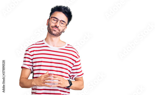 Young hispanic man wearing casual clothes hands together and fingers crossed smiling relaxed and cheerful. success and optimistic