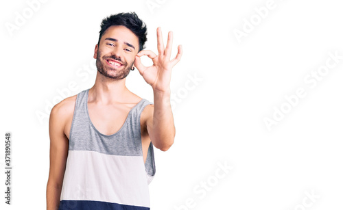 Young hispanic man wearing casual clothes smiling positive doing ok sign with hand and fingers. successful expression.