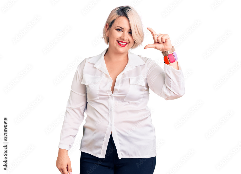 Young blonde plus size woman wearing casual shirt smiling and confident gesturing with hand doing small size sign with fingers looking and the camera. measure concept. Young blonde plus size woman wearing casual shirt smiling and confident gesturing with hand doing small size sign with fingers looking and the camera. measure concept.