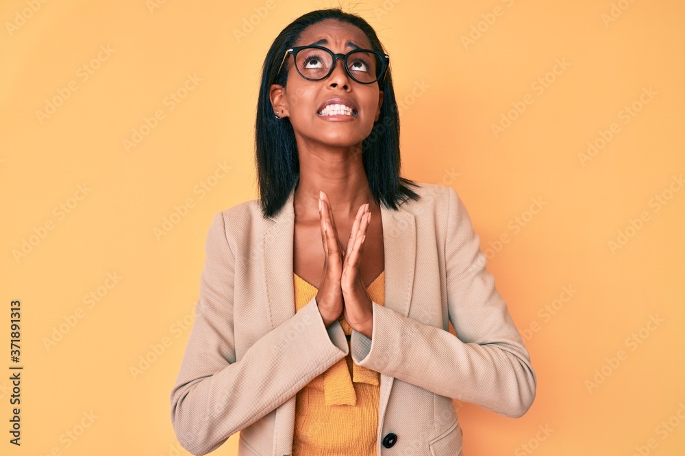 Young african american woman wearing business clothes begging and praying with hands together with hope expression on face very emotional and worried. begging.