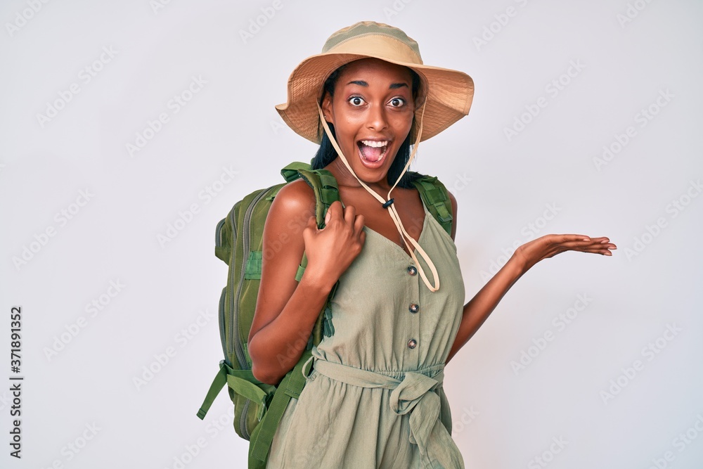 Young african american woman wearing explorer hat celebrating victory with happy smile and winner expression with raised hands Young african american woman wearing explorer hat celebrating victory with happy smile and winner expression with raised hands