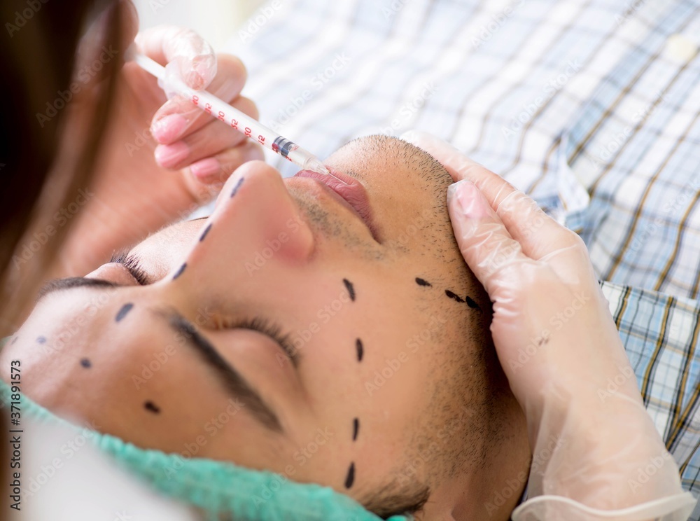 Plastic surgeon preparing for operation on man face Plastic surgeon preparing for operation on man face