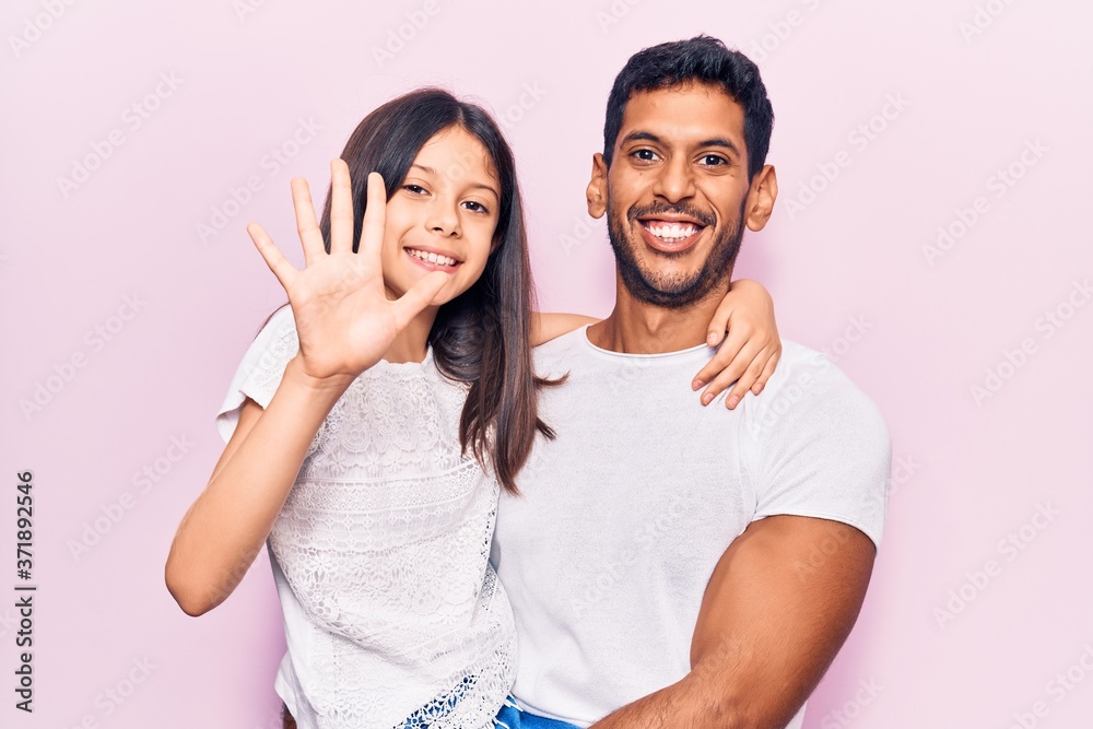 Young father and daughter wearing casual clothes showing and pointing up with fingers number five while smiling confident and happy. Young father and daughter wearing casual clothes showing and pointing up with fingers number five while smiling confident and happy.