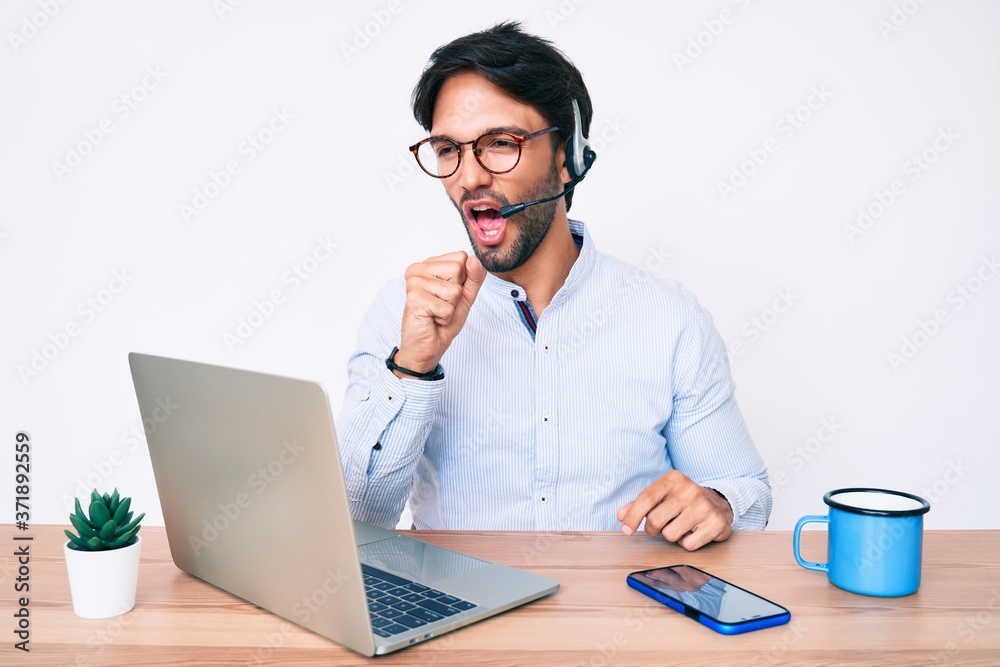 Handsome hispanic man working at the office wearing operator headset feeling unwell and coughing as symptom for cold or bronchitis. health care concept. Handsome hispanic man working at the office wearing operator headset feeling unwell and coughing as symptom for cold or bronchitis. health care concept.